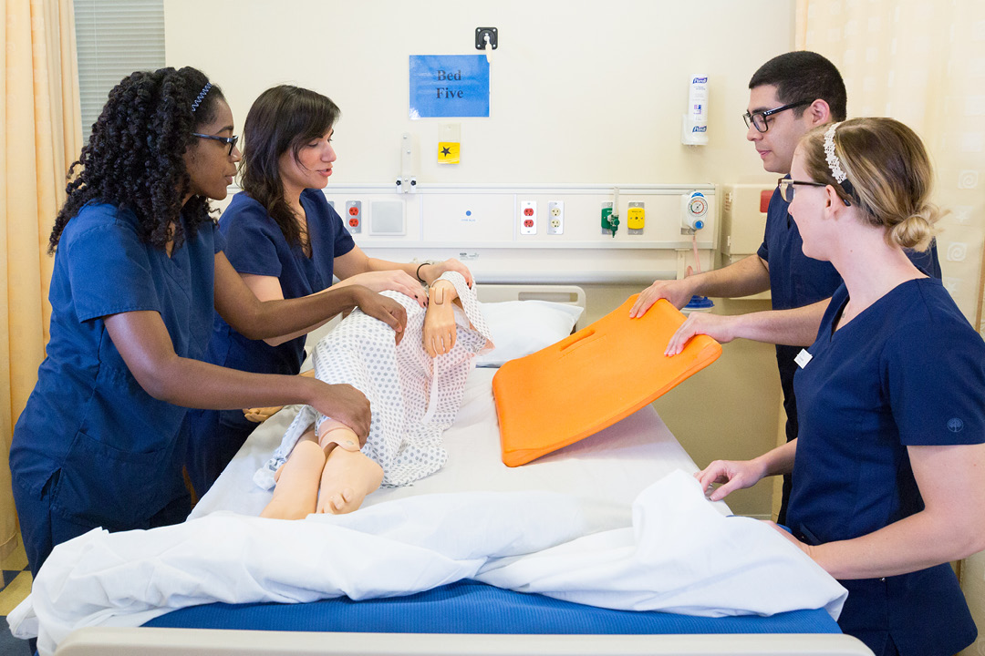 School of Nursing students practicing placing a board under a dummy doll