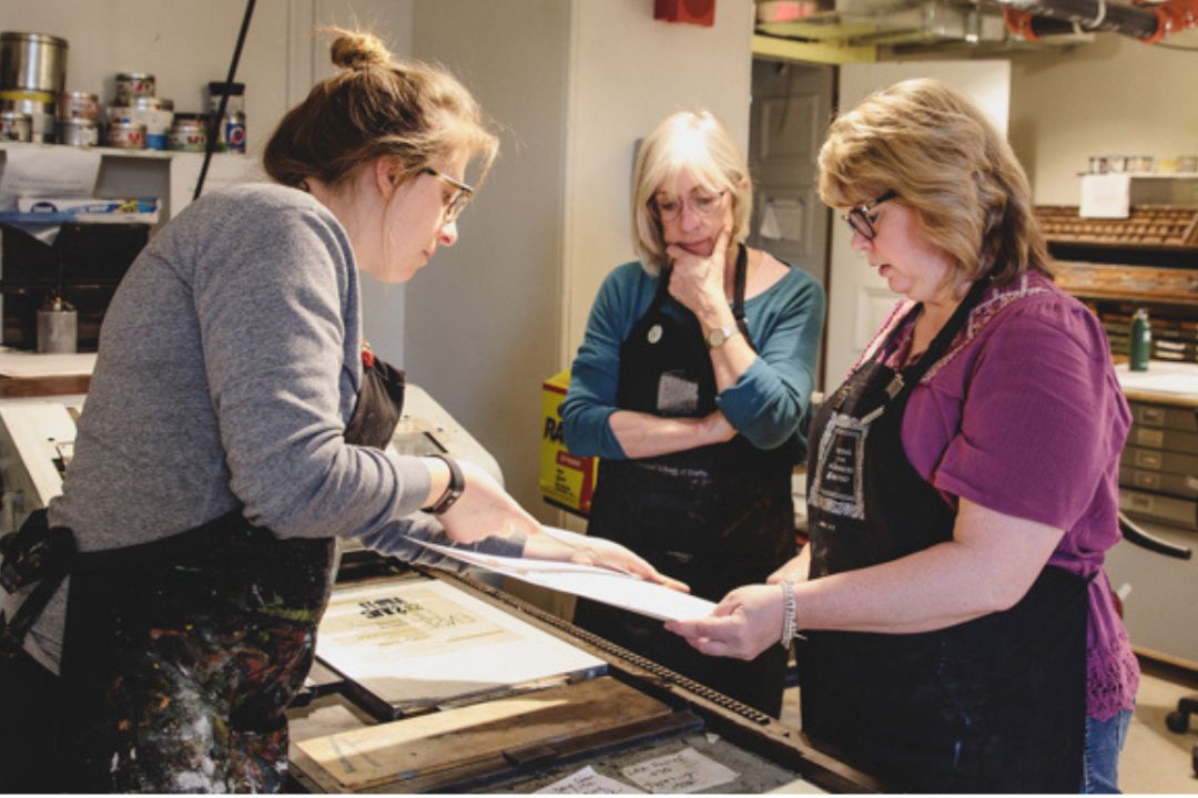 Three women discussing a painting in a studio environment